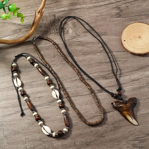 Detail of bohemian ocean necklaces with wood beads, shells and shark tooth pendant on wood