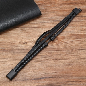Detail of multi-layer black braided leather bracelet with metal dumbbell accents