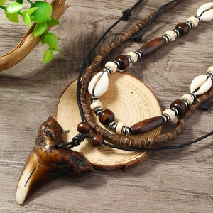 Detail of bohemian ocean style necklace with shark tooth pendant and wooden beads