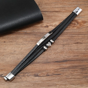 Detail of multilayer woven leather bracelet with magnetic clasp and heart charm on wood