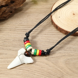 Detailed close-up of shark tooth pendant with colorful tribal beads on a wooden background