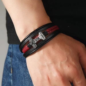 Close-up of a men's braided leather bracelet featuring a silver Mjölnir Viking hammer pendant