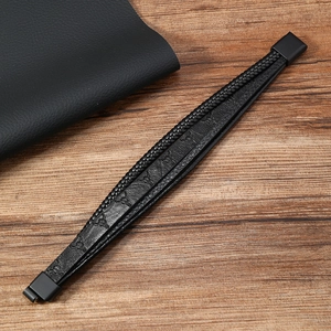 Macro detail of braided black leather bracelet with bull head motif and magnetic clasp