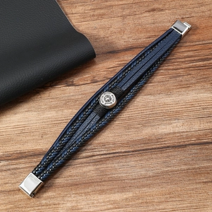 Detailed macro view of multilayer braided leather bracelet with silver compass charm and clasp