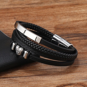 Macro detail of men's multilayer black braided leather bracelet with heart metal charms