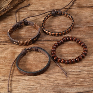 Detailset aus vier Vintage-Lederarmbändern und Holzperlen auf dunklem Holzgrund
