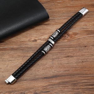 Détail du bracelet tressé en cuir noir avec perles en métal gravé et fermoir magnétique
