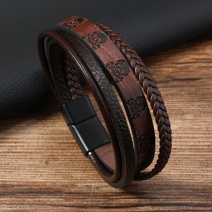 Détail d'un bracelet en cuir multicouche avec motif tête de mort et cordons tressés