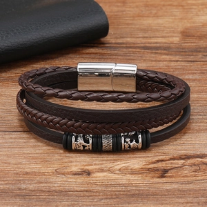 Close-up of multilayer leather bracelet with braided strands and silver lion charm