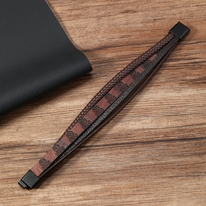 Détail d'un bracelet multicouche en cuir avec motif tête de mort et fermoir noir