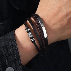Detail of multi-layer brown braided leather bracelet with silver heart charm on wrist