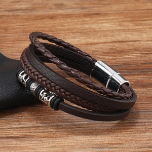Detail of multi-layer brown braided leather bracelet with engraved beads and magnetic clasp