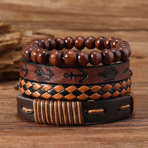 Makro-Detail eines 4-teiligen Sets handgefertigter Vintage-Lederarmbänder auf Holz