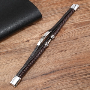 Close-up of a men's layered leather bracelet with brown braid and silver steel buckle