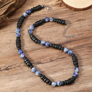 Collar gargantilla bohemio con piedras jaspeadas azules y cuentas de coco sobre madera
