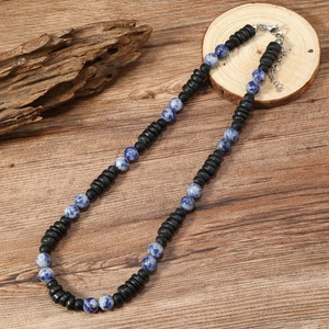 Detalle de collar bohemio con cuentas de piedra natural azul y discos de coco negro