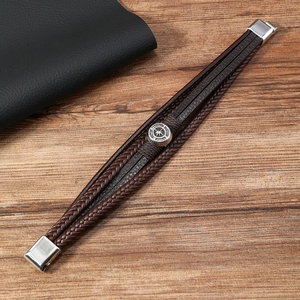 Detail of multi-layer braided leather bracelet with silver compass charm and magnetic clasp