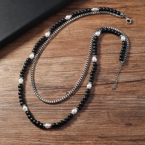 Détail d'un collier double avec perles noires mates, perles blanches et chaîne vénitienne