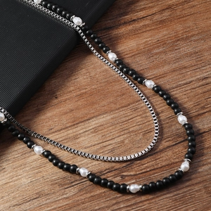 Détail du collier double couche pour homme avec perles noires mates et chaîne en acier