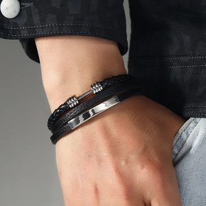 Detail view of handmade braided leather bracelet with silver accents on a man's wrist