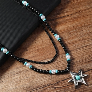 Détail d'un collier double couche avec perles noires mates et pendentif pentagramme bleu