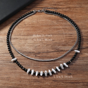 Détail d'un collier double couche avec perles noires mates et perles baroques sur bois
