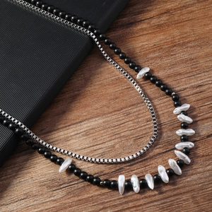 Détail d'un collier double épaisseur avec perles noires mates et perles baroques sur acier