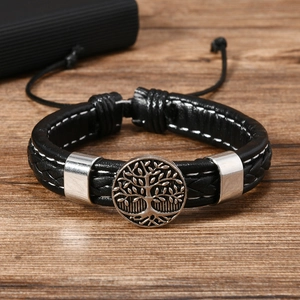 Close-up of vintage leather bracelet featuring tree of life charm on a wooden surface