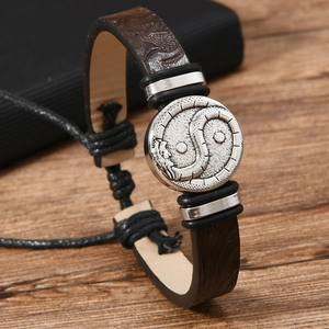 Macro shot of brown leather bracelet featuring an embossed yin-yang dragon metal emblem