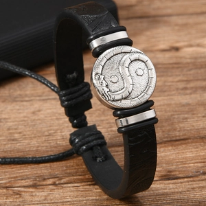 Close-up of woven leather bracelet with silver Yin Yang dragon magnetic clasp on wood