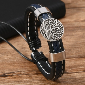 Macro detail of hand-woven leather layers and Tree of Life metal charm on bracelet