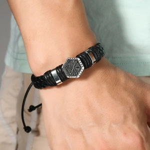 Macro shot of a braided leather men's bracelet featuring a runic engraved hexagon charm