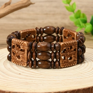 Détail d'un bracelet bohème multicouche avec des blocs de bois à fleurs gravées