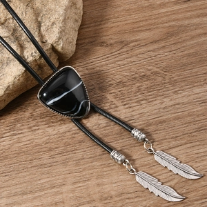 Western Bolo Tie mit dreieckigem Türkisstein und Federanhänger auf Holzoberfläche