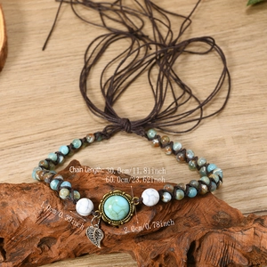 Bohemian beaded turquoise necklace with feather pendant and adjustable brown cord on wood