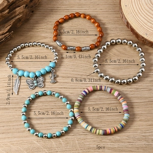 Detail of 5-piece bohemian beaded bracelet set with cactus and butterfly charms on wood