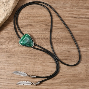 Detail von Türkis-Bolo-Tie mit silbernen Feder-Anhängern auf rustikalem Holzgrund