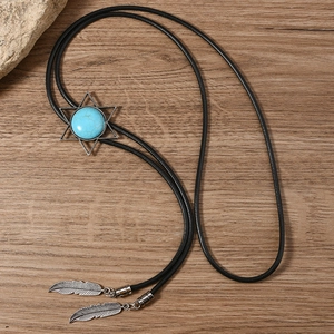 Close-up of a vintage bolo tie with a turquoise star slider and silver feather charms