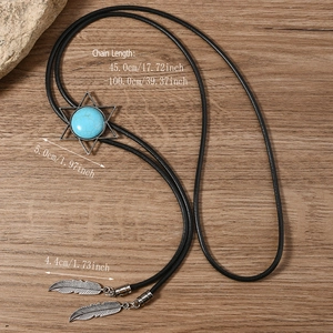 Detail of vintage bolo tie with turquoise star pendant and feather ends on wood background