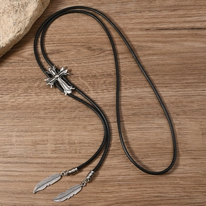 Close-up of vintage silver cross slide and feather pendants on black bolo tie rope