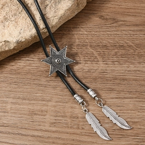Detail of vintage bolo tie showing star buckle and feather pendants on wood texture