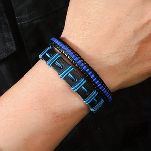 Close-up of men's layered leather and rope woven bracelets in black and royal blue