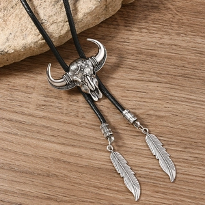 Detailed view of silver bull skull bolo tie with woven cord and feather metal charms