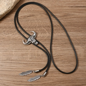 Detail of vintage silver bull head bolo tie with woven black cord and feather charms