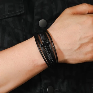 Detail of multi-layer black leather bracelet with cross magnetic clasp on male wrist