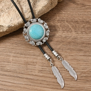 Vintage bolo tie detail featuring a turquoise stone with braided cord and feather tips