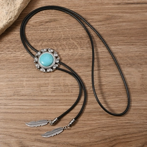 Close-up of vintage silver bolo tie with turquoise stone and metal feather charms