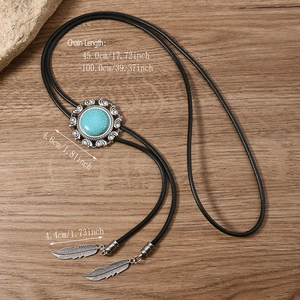 Detail of vintage bolo tie with turquoise centerpiece and metallic feather pendants