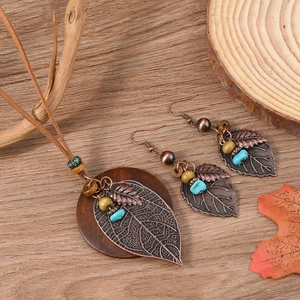 Retro leaf pendant necklace and earrings set with turquoise and wooden beads on wood background