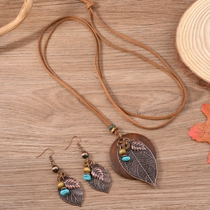 Vintage boho wooden disc and leaf pendant jewelry set on a natural wood surface